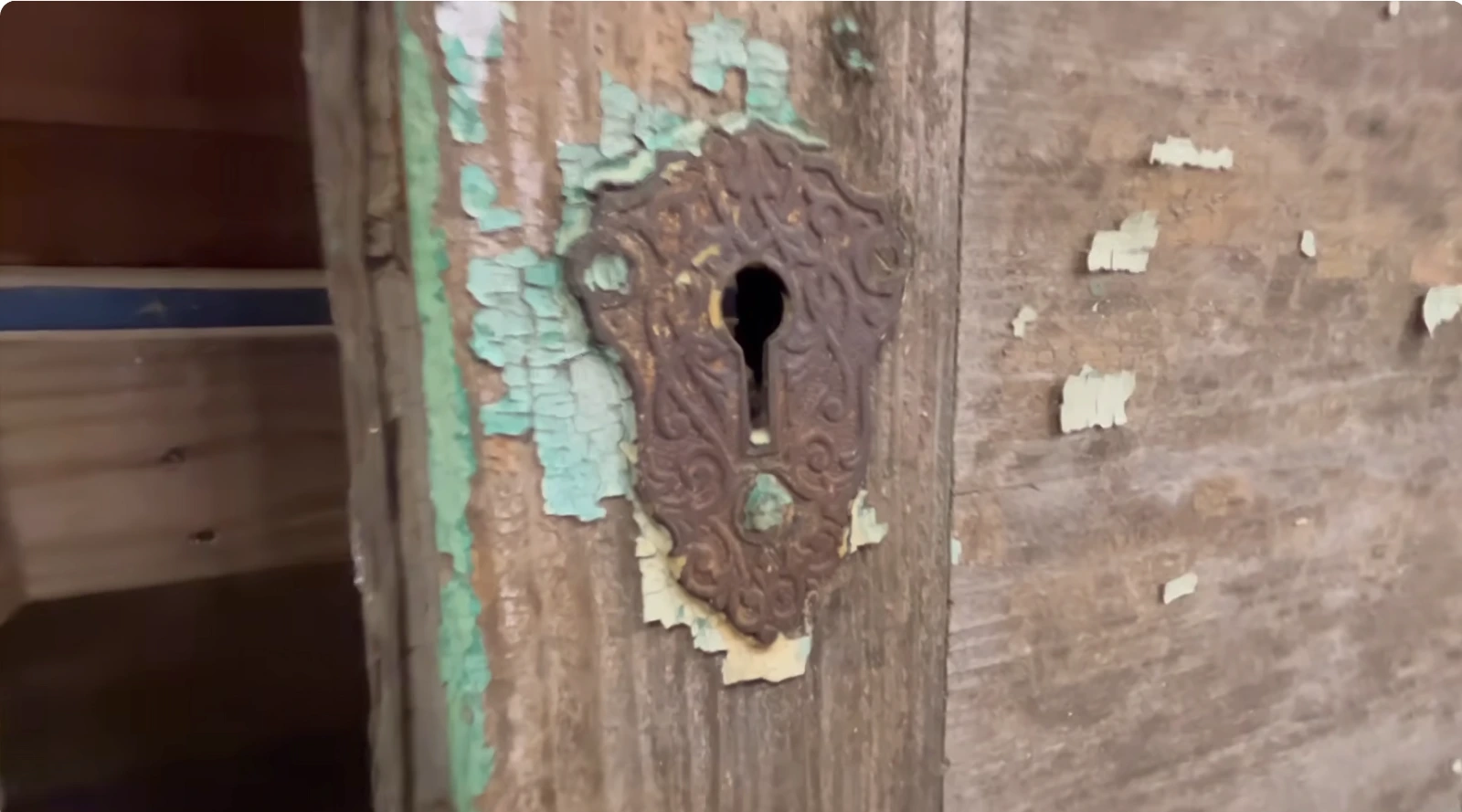 Close-up view of antique door hinge showing hand-forged construction irregular fastener holes and authentic patina